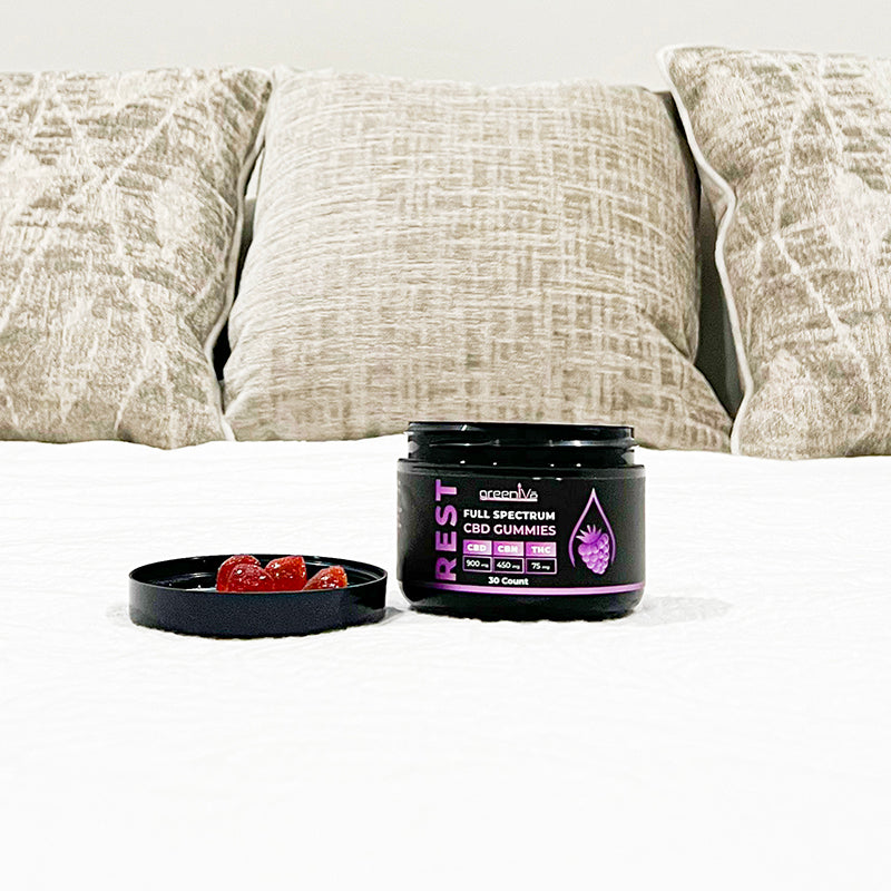 Container of 'REST' full spectrum CBD gummies on a couch