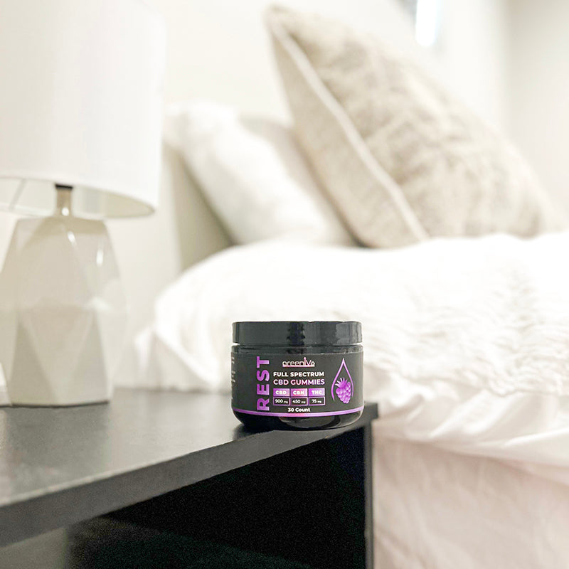 Jar of Rest Full Spectrum CBD Gummies on a nightstand with a blurred background