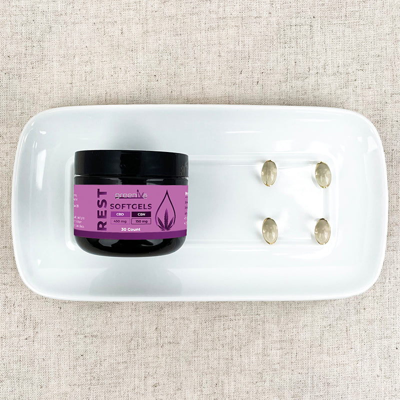 Jar of 'REST' softgels on a white plate with capsules on a textured beige background