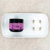 Jar of 'REST' softgels on a white plate with capsules on a textured beige background