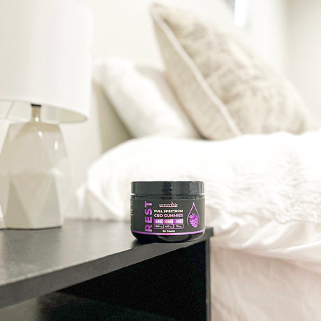 Jar of Rest Full Spectrum CBD Gummies on a nightstand with a blurred background