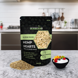 Packaging of greenLife Hemp Hearts on a kitchen counter with seeds and a bowl of fruit.
