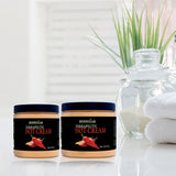 Two jars of Therapeutic Hot Cream on a reflective surface with a blurred plant and towels in the background.